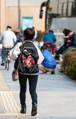 TOKYO, JAPAN - NOVEMBER 7, 2017: A woman in a jacket with the inscription Japan on a city street. Copy space for text.