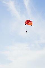 Three people are gliding using a parachute on the background of the blue sky. Copy space. Beach entertainment concept.