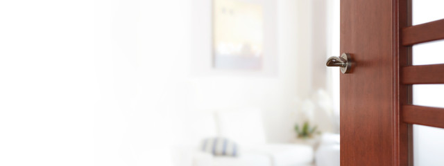 Interior design banner - blurred view through opened wooden door to a modern living room or...