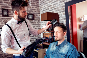 Hairdresser adjusts hair a customer with a comb