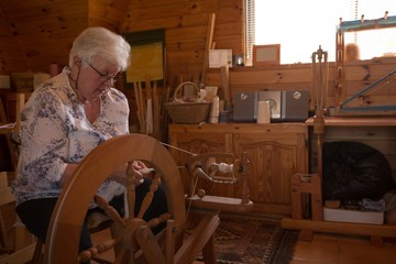 Senior woman weaving silk at shop