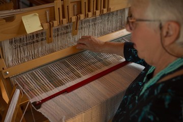 Senior woman weaving silk at shop