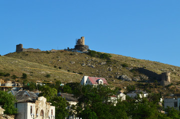a medieval fortress on top of a hill. at the foot of the mountain there is a settlement.