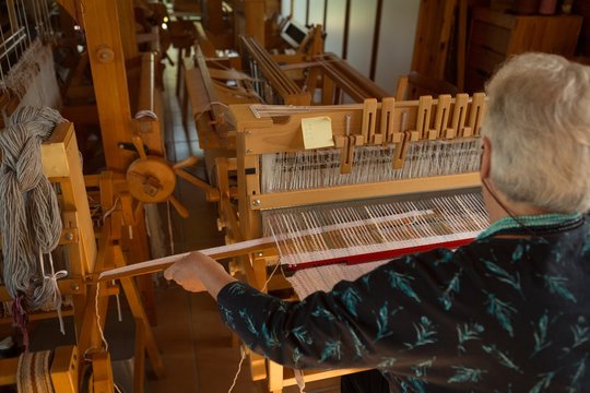 Senior woman weaving silk at shop - Powered by Adobe
