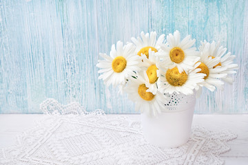 White daisy flowers in white vase on light blue background. Holiday background, copy space. Valentine Day, Mothers day, birthday concept.