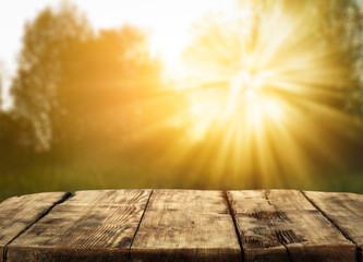 Naklejka na ściany i meble Autumn background of wooden desk and landscape with sun light. Free space for your product. 