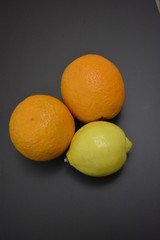 Fresh fruits, two orange oranges with one yellow lemon on an interesting matte background