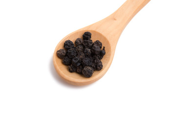 black dried pepper in wooden spoon isolated on the white