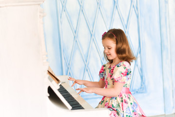little girl in white dress playing the piano. Music and art concept. School of Music