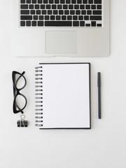 Feminine home office table desk frame. Laptop, notepan and pen, aromatic candle and cat eyewear. Flat lay, top view. Trendy minimalistic concept on the white background. Monochrome colors.