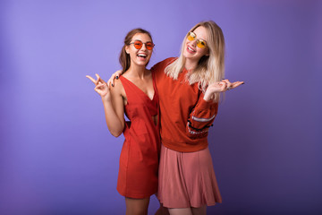 Studio lifestyle portrait of two best friends hipster girls wearing stylish bright orange outfits,...