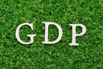 Wood alphabet in word GDP (abbreviation of Gross domestic product or Good distribution practice)on artificial green grass background