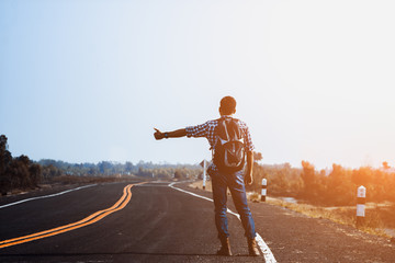 Young Man Hitchhiking on a City Road