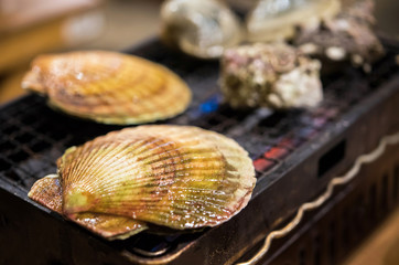 Mollusks are cooked in a cafe on fire, Tokyo, Japan. Close-up.