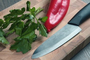 ceramic knife on a kitchen board with pepper and herbs