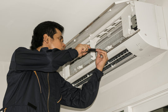 Air conditioner repairers in blue uniform are checking and repair air hanging on the wall.