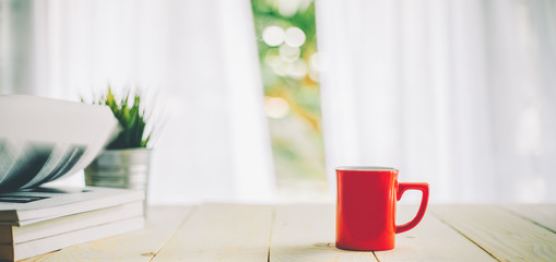 cup of coffee on wood table top and blur of curtain with window  background
