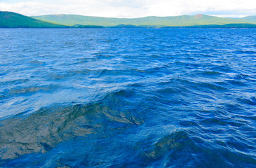 Sea surface with slight rippling water with a mountain landscape in the background