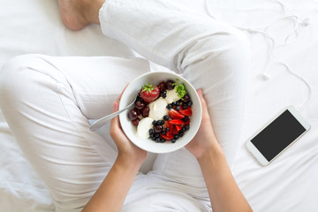 Healthy eating concept. Women's hands holding bowl with cottage cheese with cream, strawberry,...