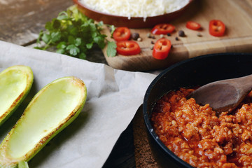 Preparation zucchini halves stuffed with meat and vegetable. Healthy food concept. Ingredients for stuffed zucchini with meat, vegetables and cheese. Foods background. Diet concept.