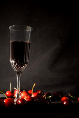 Cherry liqueur in a crystal fouger and scattered cherries  on a black background