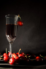 Cherry liqueur in a crystal fouger and scattered cherries  on a black background