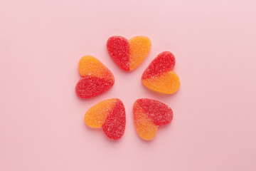Heart shaped candy red and orange color on a pink background. Five jelly candies forming flower viewed from above. Top view