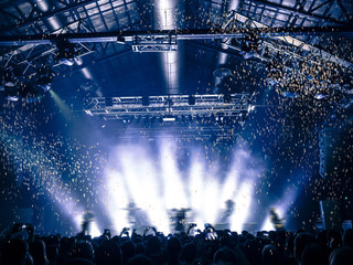 Rain of confetti falling on a concert crowd in front of a lit stage