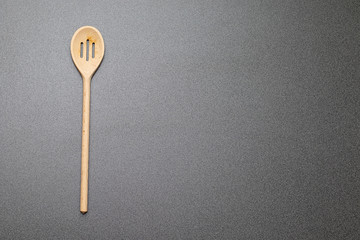 Holzkochlöffel mit Löchern auf einer grauen Arbeitsplatte in der Küche