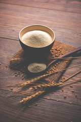 Raw unprepared semolina flour also known as Rava powder in Hindi in bowl or spoon. close-up isolated on white or moody background. selective focus