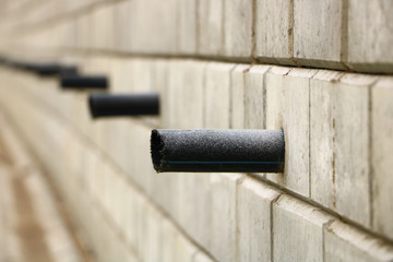 gray brick wall from which the pipes stick out
