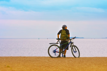 Fototapeta na wymiar the bicyclist on the shore sea looks into the distance