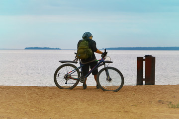 Fototapeta premium the bicyclist on the shore sea looks into the distance