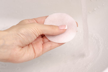 Fototapeta premium Wadded disc in hand wash off make-up washbasin bathroom