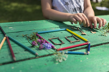 Obraz premium the child draw picture with colorful pens and flowers on the wooden green table in the nursery or school for activity concept. creative ideas for child development.