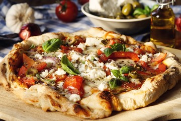 Herzhafte hausgemachte Pizza mit Feta Käse, Tomaten, Oliven und Basilikum