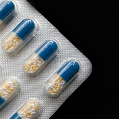 Packing blue tablets with white and yellow granules in macro photography on a black background