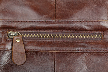 Zip fastener on a brown leather surface close-up