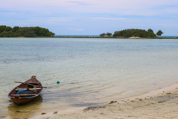 Sea view with a small boat from tropical beach with a blue sky.