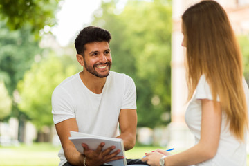 Two students studying together sitting on a bench outdoor