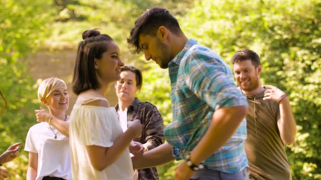 leisure, fun and entertainment concept - happy friends dancing at summer party in park