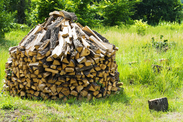 Wooden rectangular firewood for the stove and fire, stacked in a large pile on the outdoor.