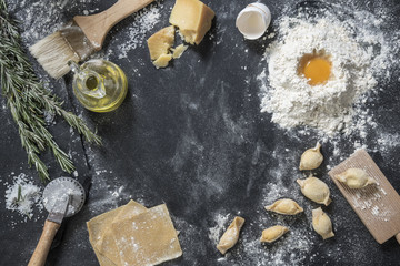 Italian cuisine ingredients over black surface. Heap of flour, olive oil and ravioli preparation to put a logo or sign