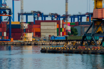 Blue electric locomotive with a cargo train on the berth of the sea port with container terminal on...