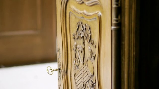 Furniture. Wooden door of drawer with carved pattern and key in keyhole. 4K