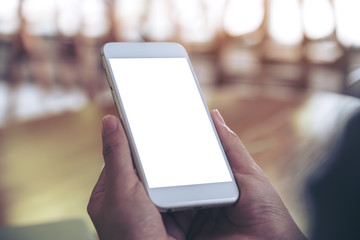 Mockup image of hands holding white mobile phone with blank desktop screen with blur background