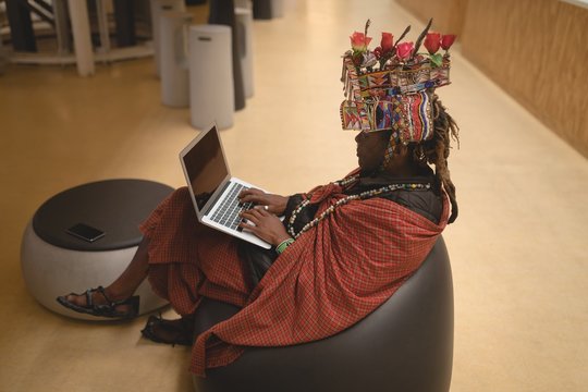 Maasai man in traditional clothing using laptop - Powered by Adobe