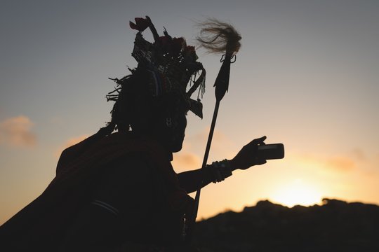 Silhouette of maasai man taking selfie with mobile phone