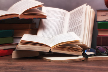 Stack of open books on the table in the background of a school blackboard. Back to school.