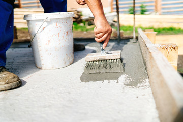 industrial construction worker using brush and primer for hydroisolating and waterproofing house
